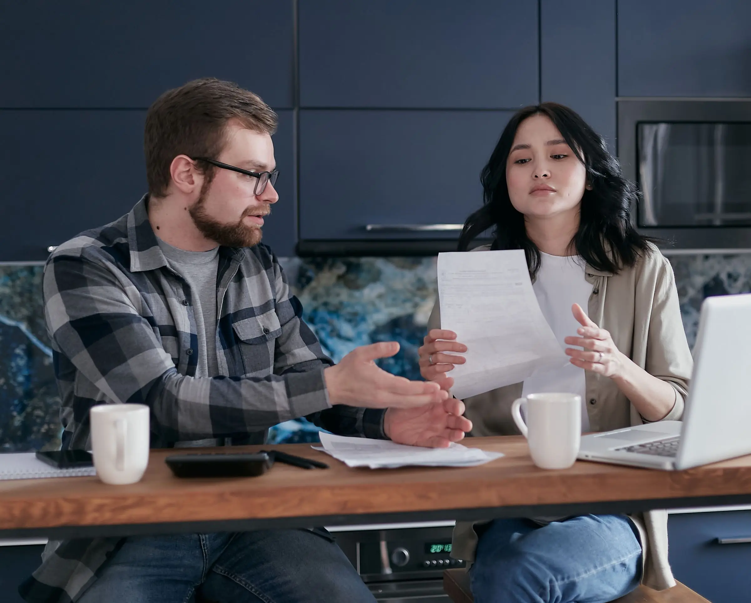 Deux personnes discutent d'un projet, documents en main, à la table de la cuisine