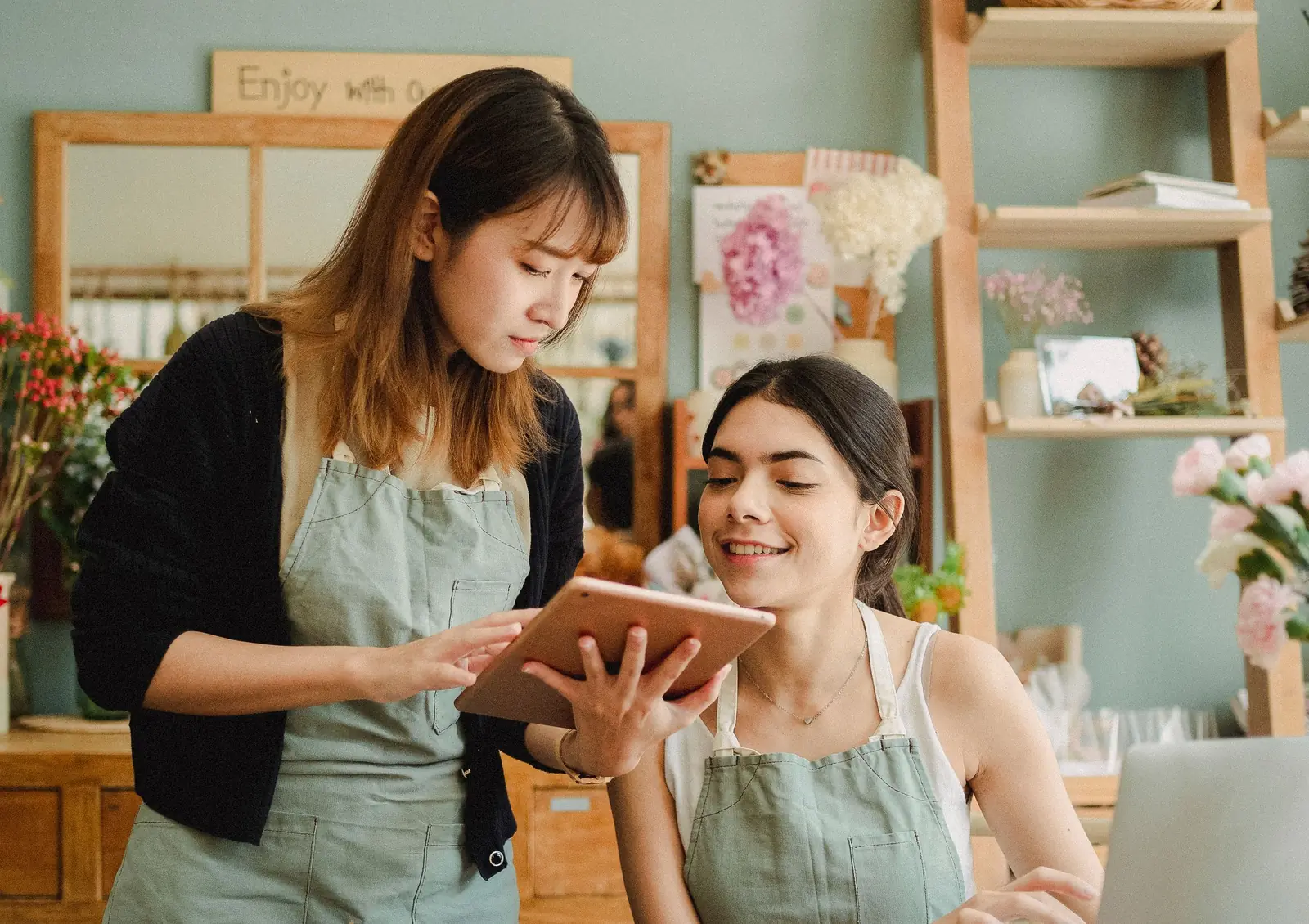 Deux commerçantes regardent ensemble une tablette dans leur boutique