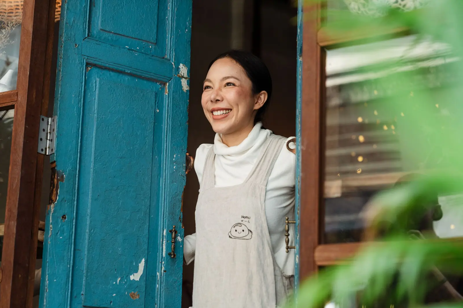 Smiling owner in the doorway of her café
